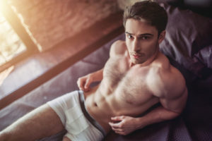 man in underwear on bed